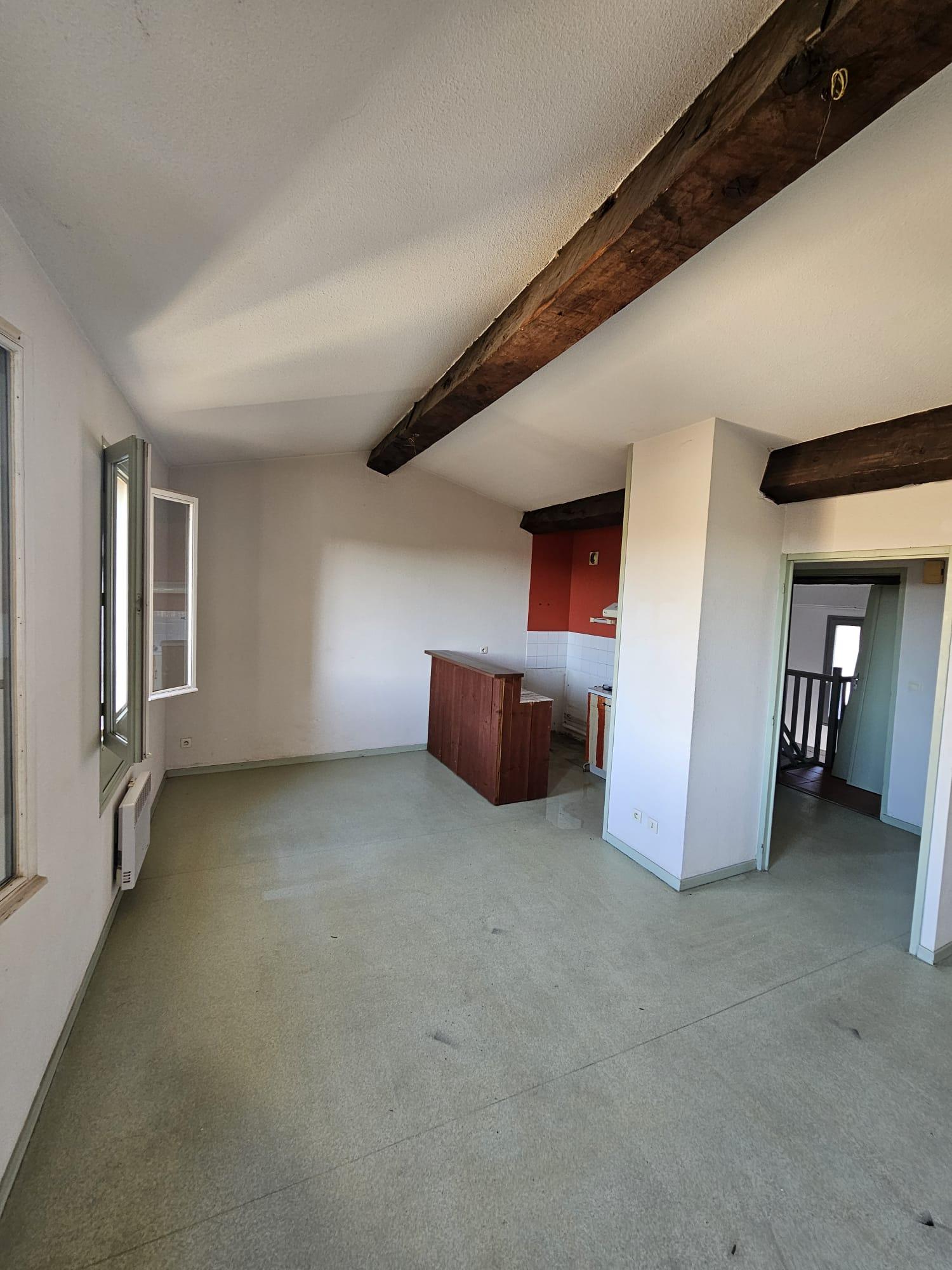 Séjour d'une maison de village à Canohès avant travaux, poutres sombres, sol souple usé, bar en bois