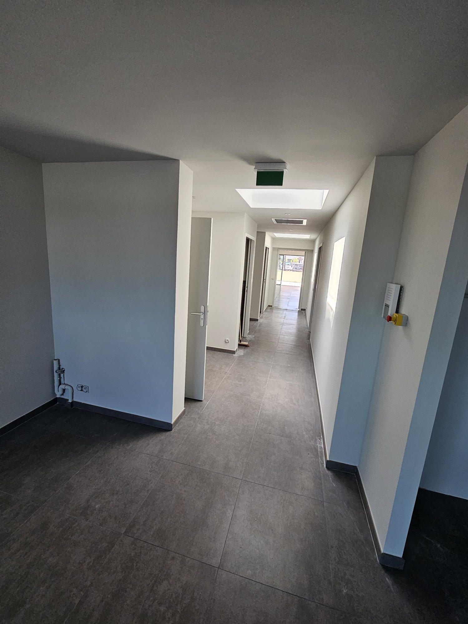 Couloir de locaux professionnels terminé, murs clairs et carrelage grand format