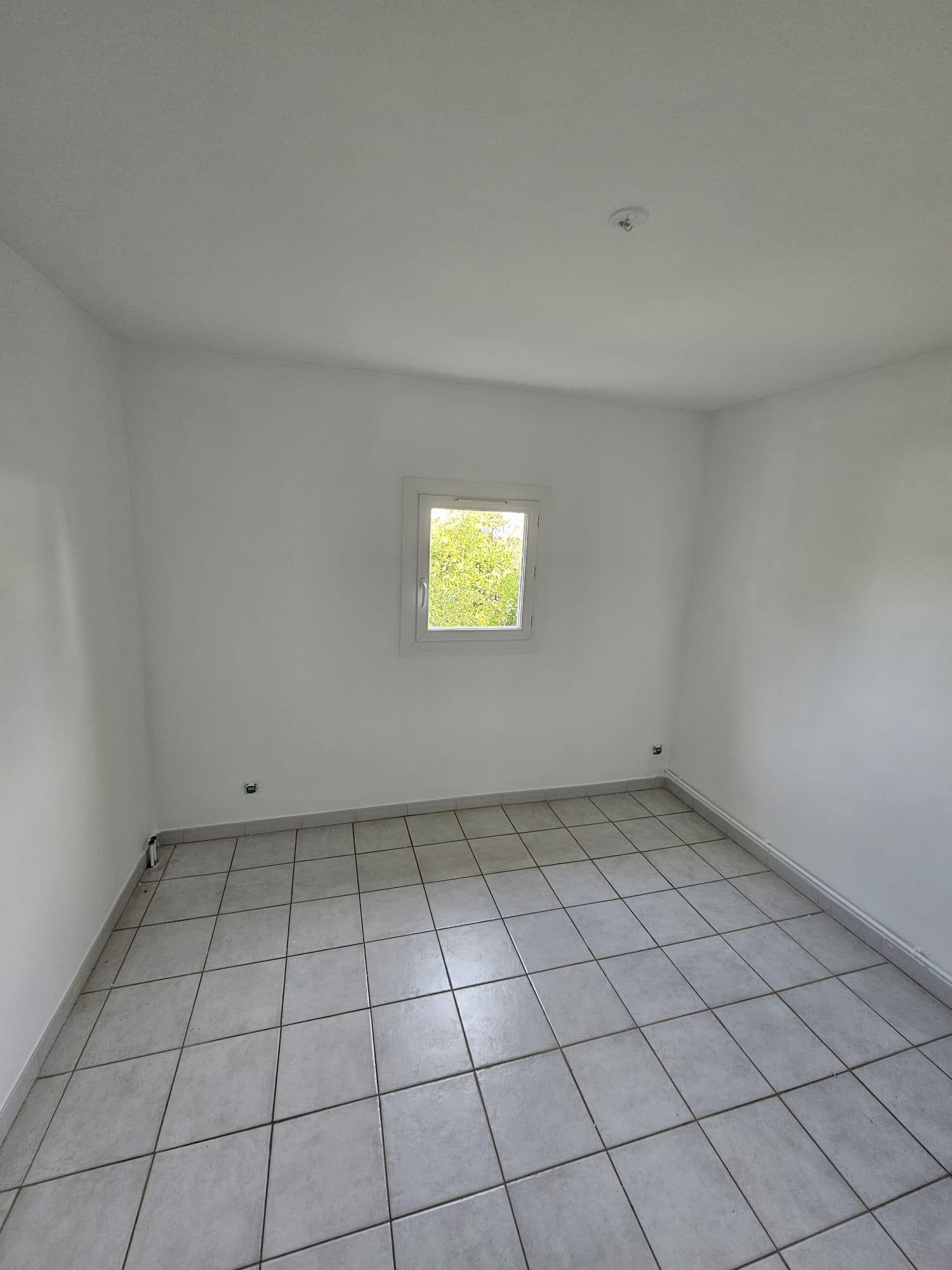 Chambre vide d'un appartement à Perpignan, murs blancs, petite fenêtre, carrelage beige